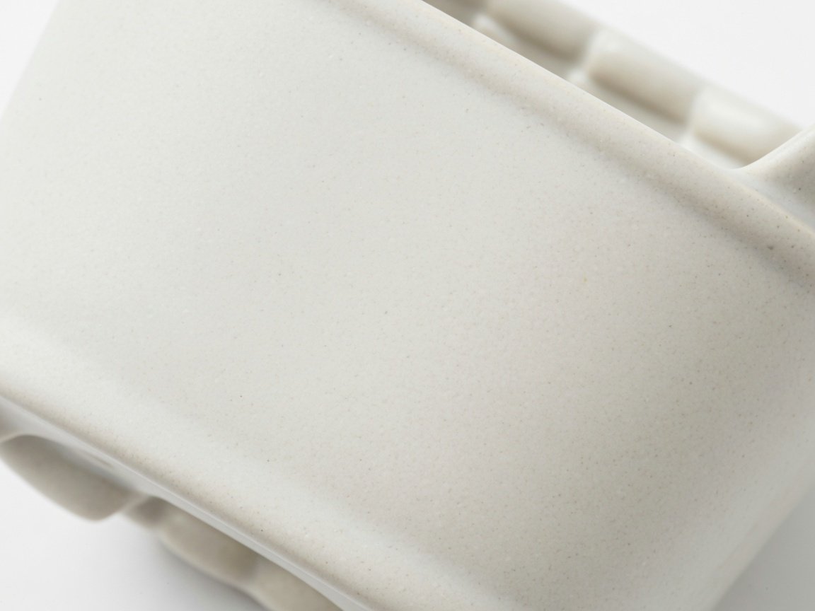 Close-up macro of a PFAS-free ceramic basket surface showing smooth even texture with no scratches, studio white